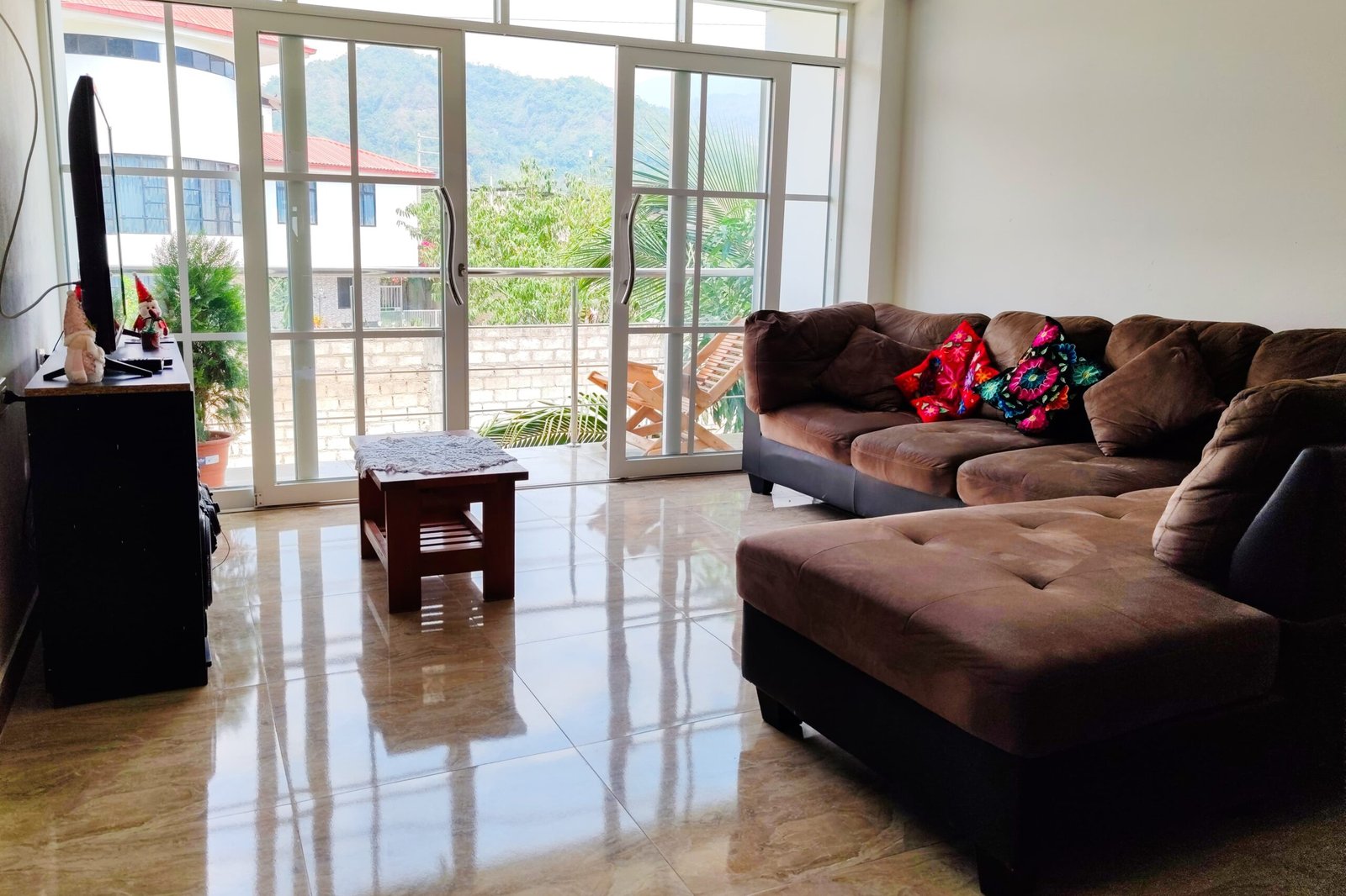 Sala acogedora y balcón en departamento familiar de hospedaje en San Ramón, Chanchamayo. Cuenta con Wifi, Netflix y balcón con vista al bosque y capacidad para familiar o grupos grandes