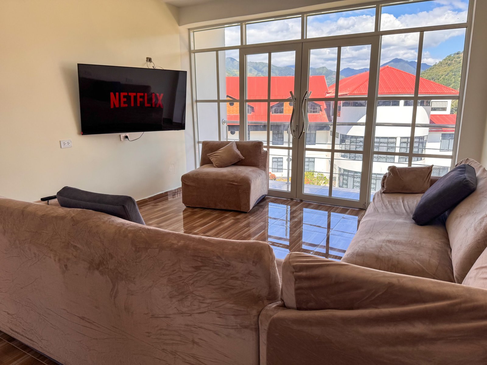 Sala moderna en departamento familiar de hospedaje en San Ramón, Chanchamayo. Cuenta con Wifi, Netflix y balcón con vista panorámica al bosque y capacidad para familias o grupos grandes